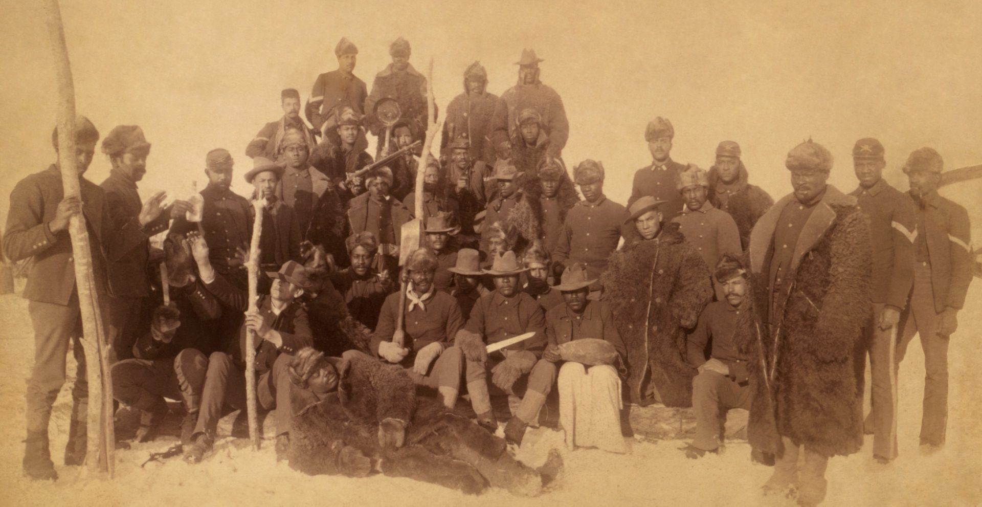 This image is of Buffalo Soldiers of the 25th Infantry and was taken at Fort Keogh, Montana.  The photograph features several soldiers in coats made of buffalo hides.